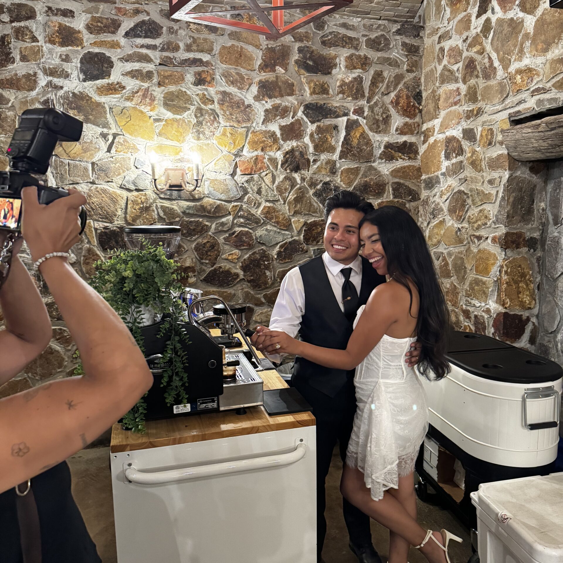 Newlywed couple standing behind a coffee cart at their wedding for a picture
